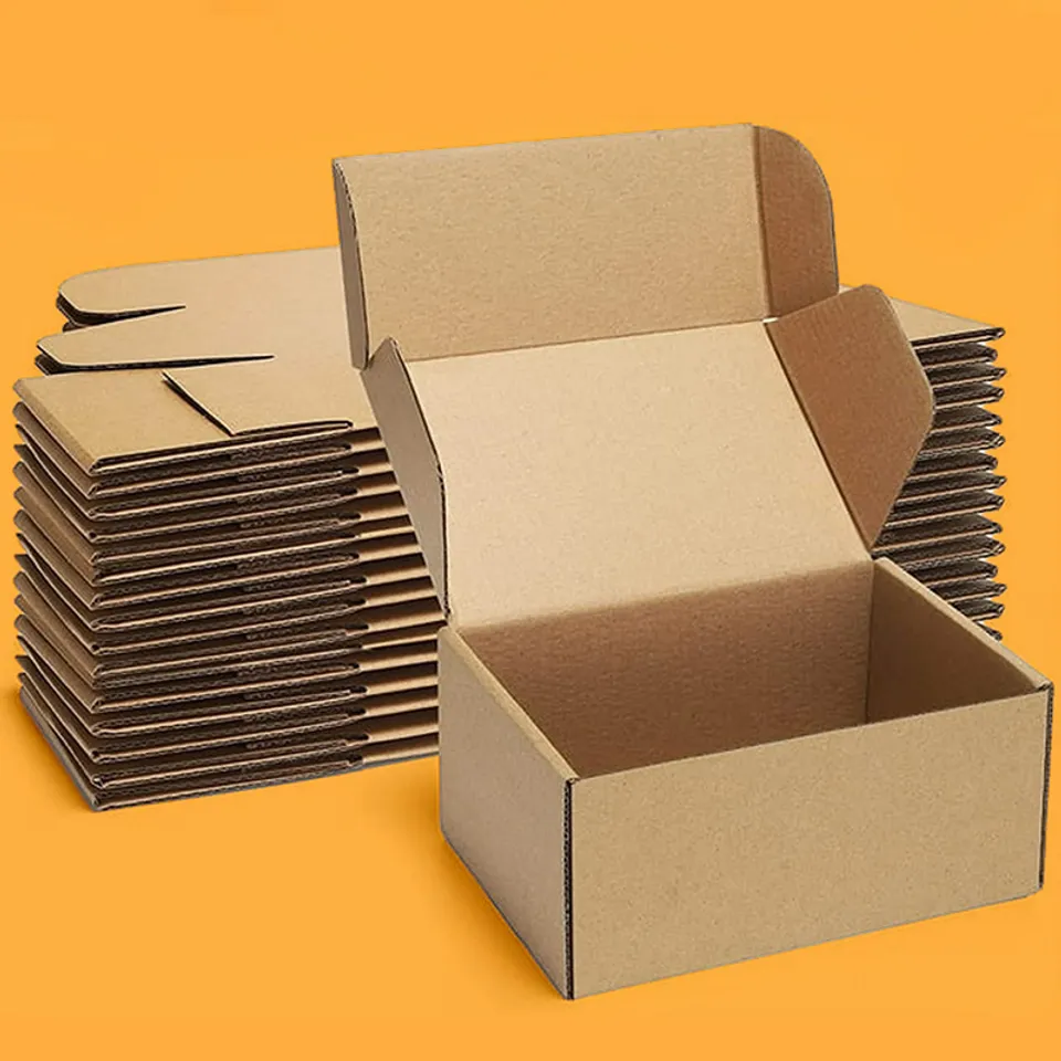 Folding Small Mailing Boxes: Open kraft folding box in front of a tall stack of flat blanks ready to fold