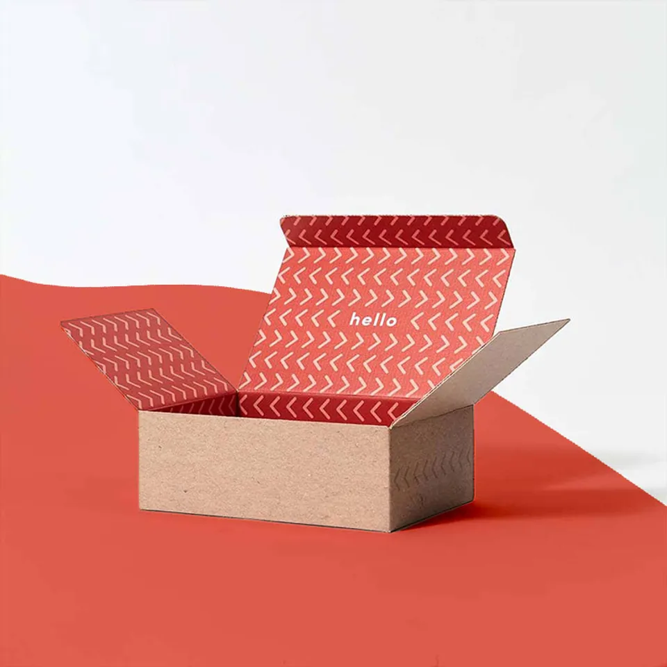 Tuck Top Mailer Boxes: Kraft base with a red patterned lid inside, side flaps folded out before the lid tucks in